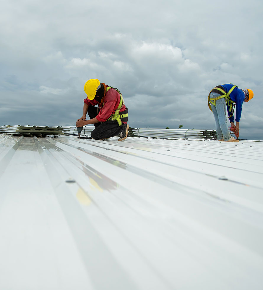 two commercial roofers working on a metal roof